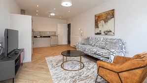 A modern living room with a sofa, a coffee table, and a TV. - Quiet Luxe Escape 65s Only (Leatherhead)