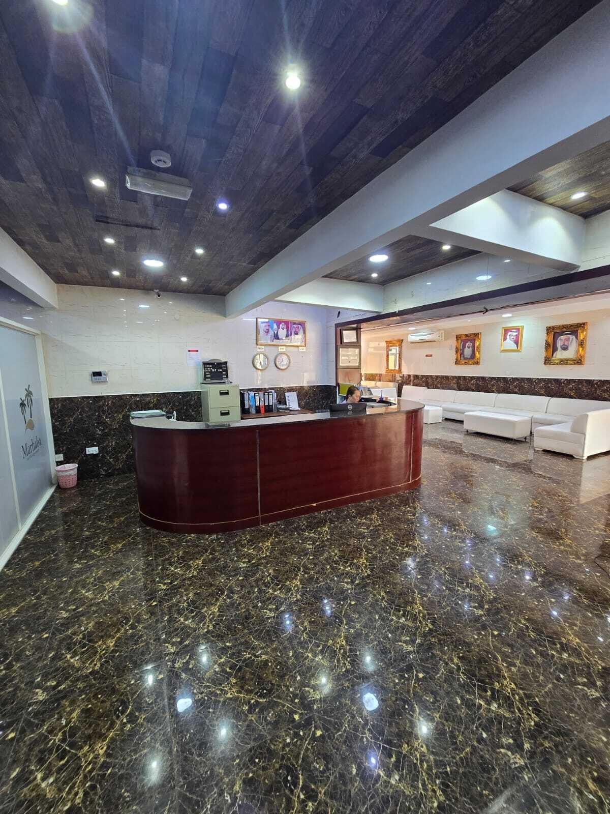 A reception area with a marble floor, a reception desk, and a seating area with white sofas.