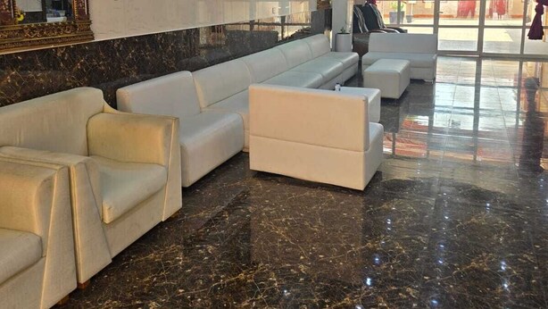 Un hall amplio con piso de mármol, un sofá blanco y un espejo grande.
