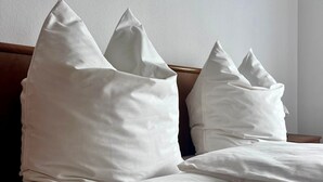 A bed with white bedding and pillows, a wooden headboard, and a plain wall. - Apartment 'Natascha' with Mountain View, Shared Terrace and Wi-Fi (Fellen)