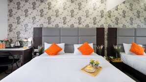 A hotel room with a large bed, two pillows, a bedside table, a desk, and a mirror. - Hotel Marigold Atnest Gachibowli (Hyderabad)