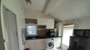 A compact kitchen with a washing machine, a microwave, and a toaster oven.