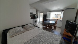 A compact bedroom with a bed, a small dining table, and a TV.