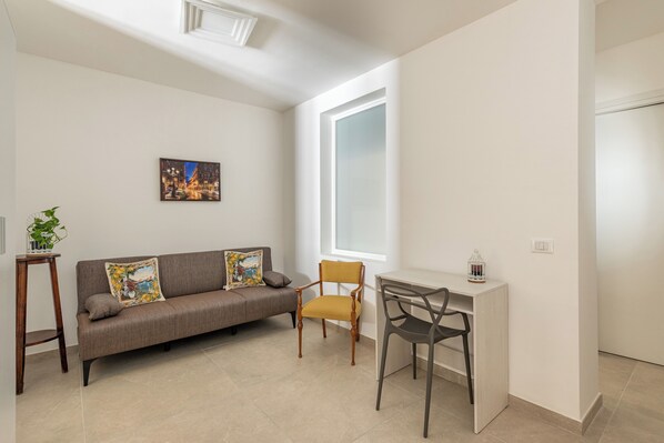 A modern living room with a sofa, a chair, a small table, and a desk.