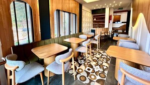 A modern restaurant interior with wooden panel walls, green cushioned seating, and patterned floor tiles. - Castello By Mediterra  (Alanya)
