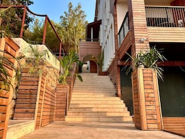 Una escalera que lleva a un edificio con barandas de madera y plantas en macetas.