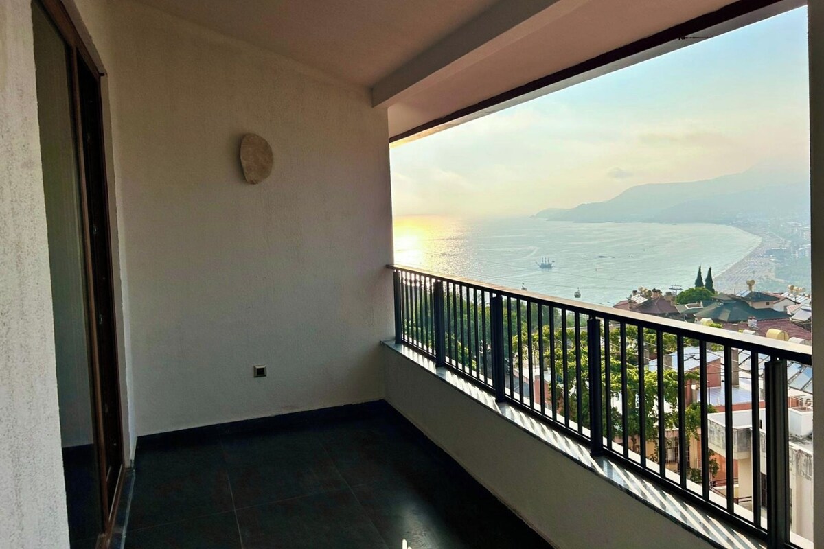A balcony with a view of the sea and a cityscape.