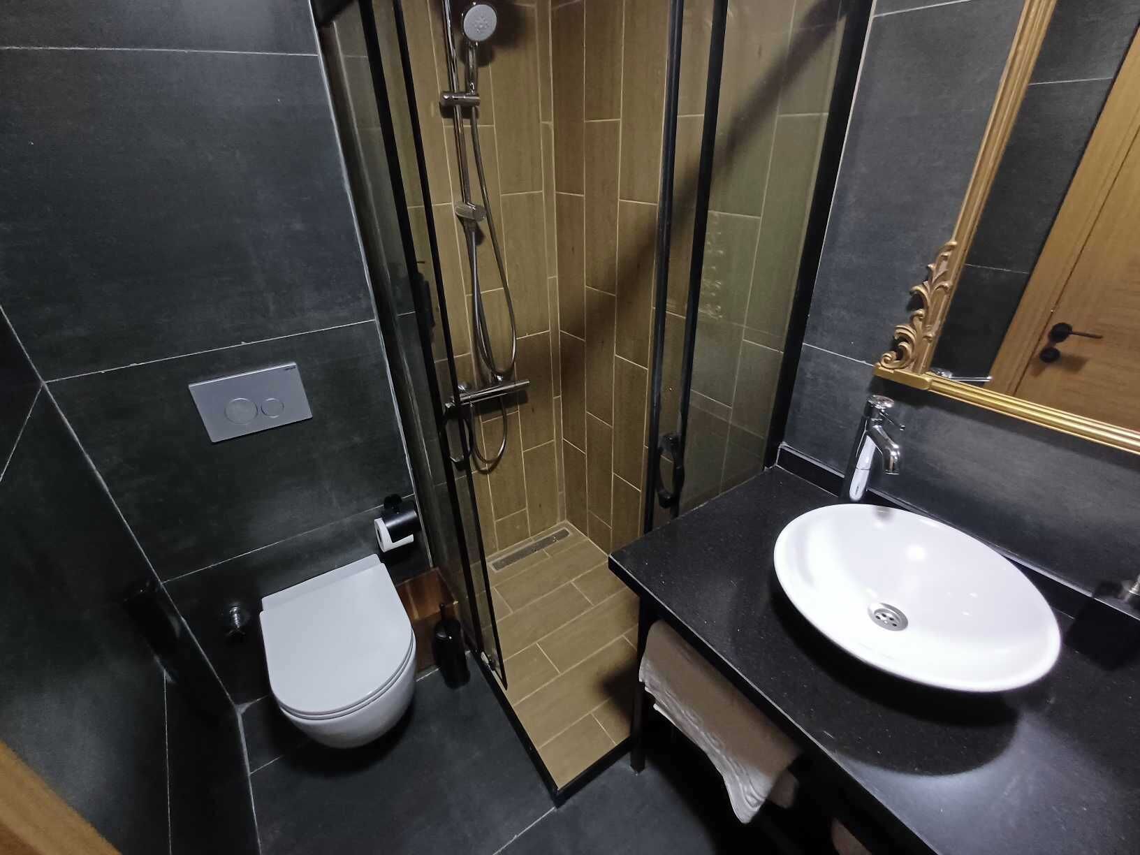 A bathroom with a toilet, shower, and sink.