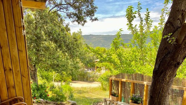 Un área de comedor al aire libre con una mesa dispuesta para dos personas, rodeada por una terraza de madera y un muro de piedra.