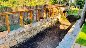 Un muro de piedra con cerca de madera y plantas en macetas.