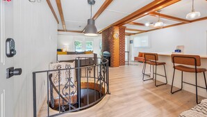 A modern interior with a wooden staircase, a kitchen area, and a seating space with bar stools. - Lakefront retreat with private dock, open living, fire pit, full kitchen & cozy indoor spaces (Radford)