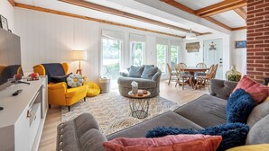A cozy living room with a sofa, armchairs, and a dining area with a table and chairs. - Lakefront retreat with private dock, open living, fire pit, full kitchen & cozy indoor spaces (Radford)