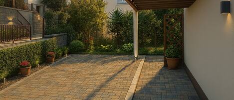 Un patio empedrado con una pérgola, plantas en macetas y un muro de piedra.