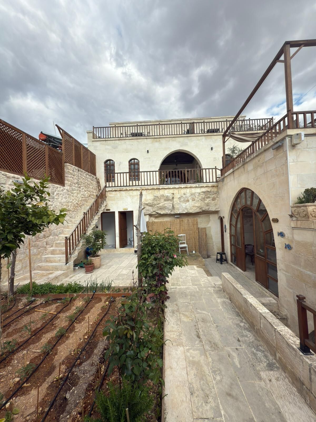 A courtyard with stone walls, a staircase, and a small garden area.