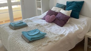 A bedroom with a bed, pillows, a white wardrobe, and a door leading to a balcony. - Apartment 'Benalmadena Home' with Sea Views, Wi-Fi and Air Conditioning (Benalmádena)