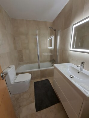 A bathroom with a toilet, a bathtub, a shower, a sink, and a mirror.