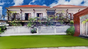 A two-story building with a red-tiled roof, a white exterior, and a balcony with plants. - Collection O Bali Sanur near Bali Mandara Hospital (Denpasar)