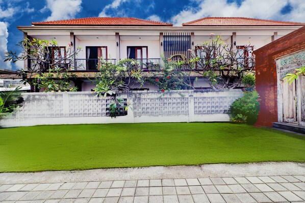 A two-story building with a red-tiled roof, a white exterior, and a balcony with plants. - Collection O Bali Sanur near Bali Mandara Hospital (Denpasar)