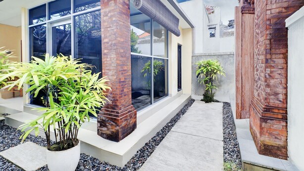 A modern building with large windows, brick pillars, and potted plants. - Collection O Bali Sanur near Bali Mandara Hospital (Denpasar)