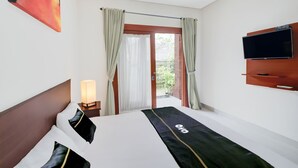A hotel room with a bed, a TV mounted on the wall, and a window with curtains. - Collection O Bali Sanur near Bali Mandara Hospital (Denpasar)