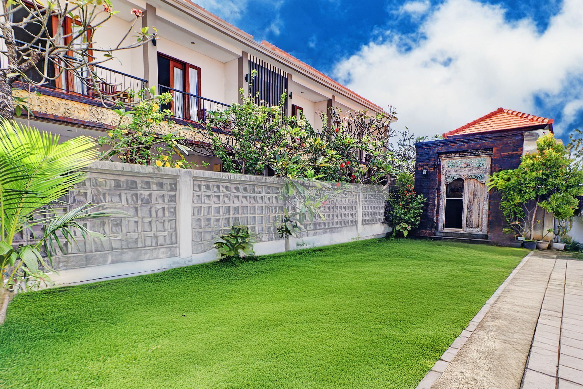 Una casa moderna con un césped cuidado, un muro de piedra y un pequeño jardín.