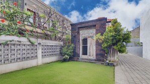 A courtyard with a small garden, a decorative door, and a brick wall. - Collection O Bali Sanur near Bali Mandara Hospital (Denpasar)