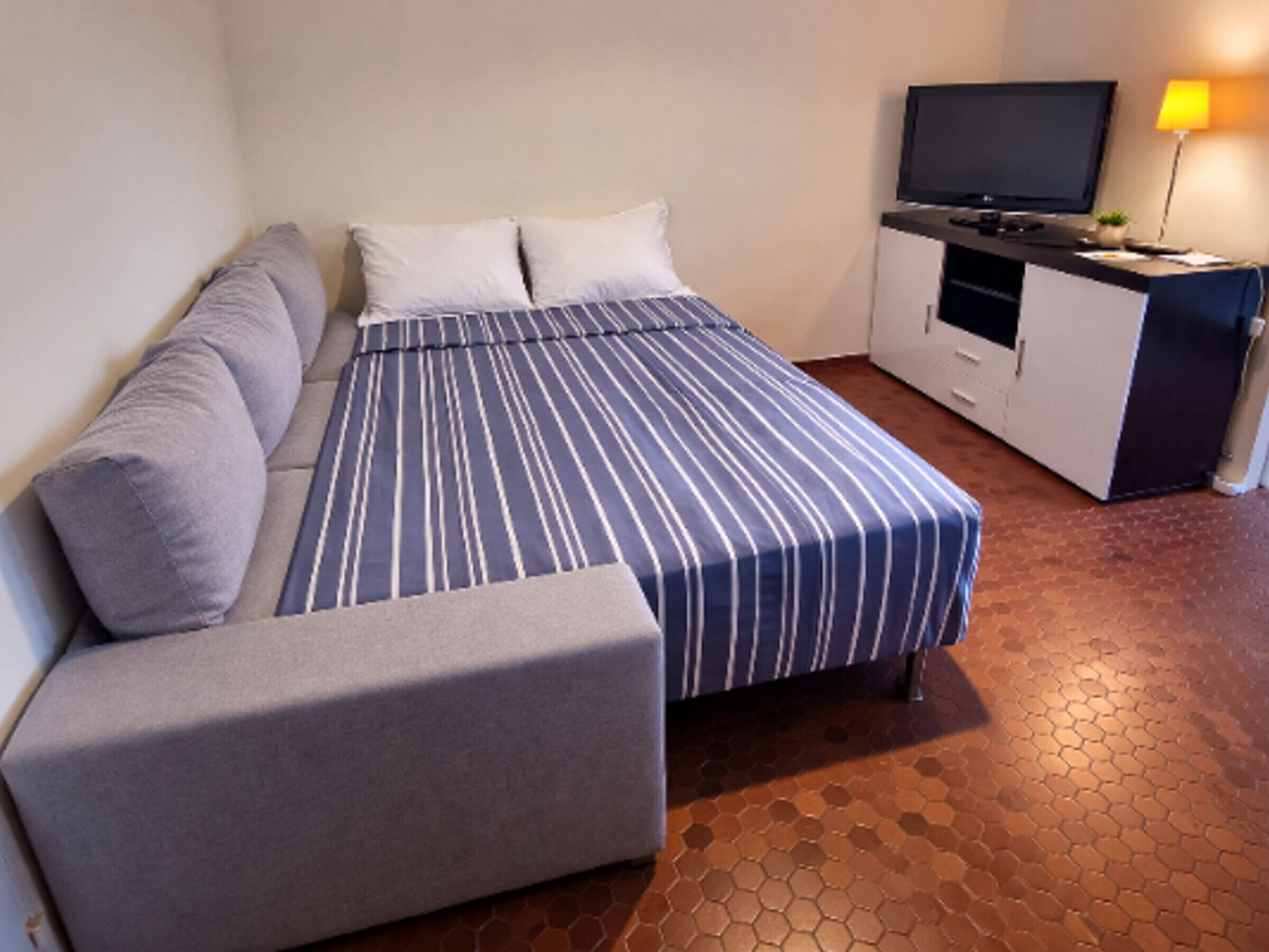 Une chambre d’hôtel avec un lit, un canapé, une télévision et un bureau.