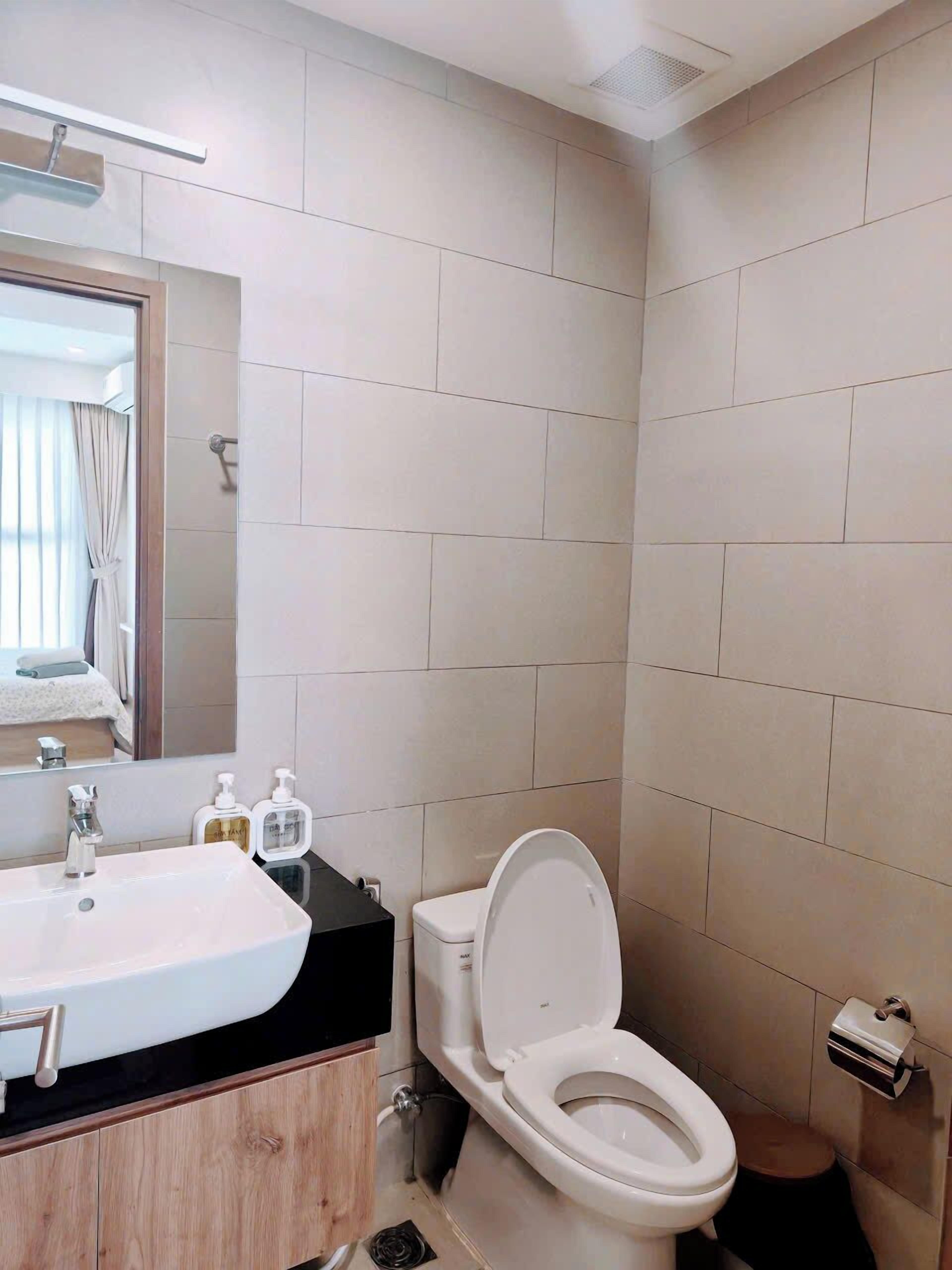 A modern bathroom with a white sink, mirror, and toilet.