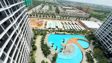 A modern residential complex with a central swimming pool, surrounded by landscaped areas and high-rise buildings.