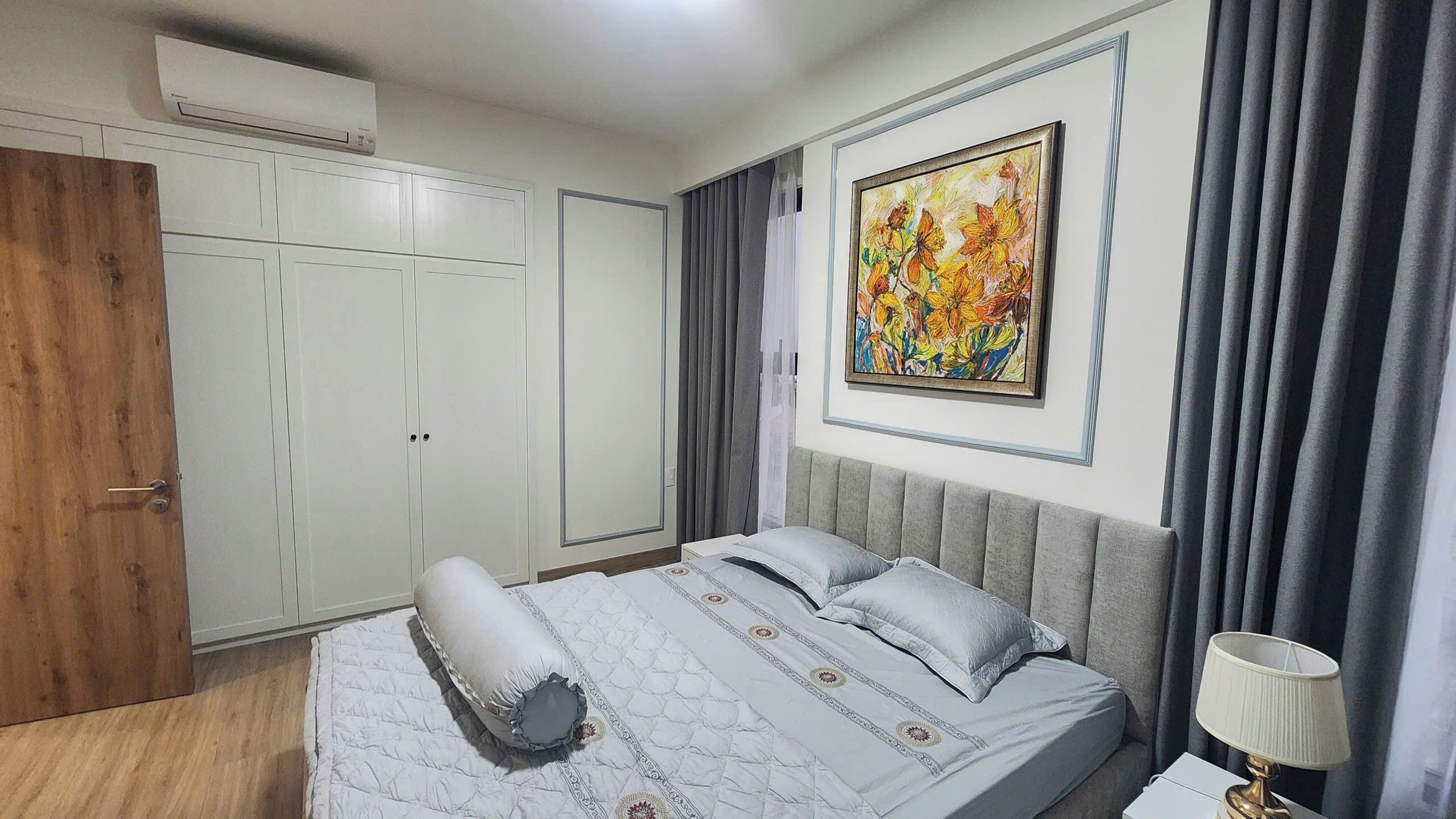 Un dormitorio con cama, armario, cuadro y cortinas.