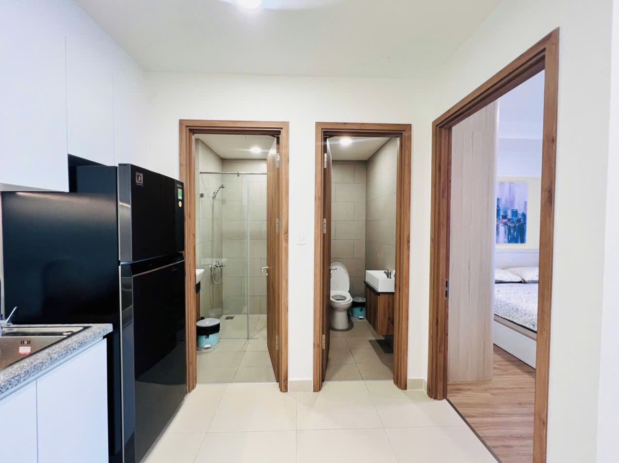 Een kleine kamer met een kitchenette, een douche en toilet.