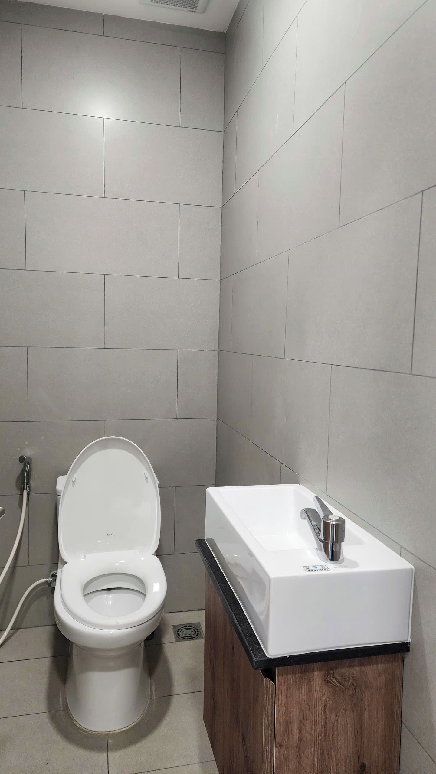 Ein modernes Badezimmer mit Toilette, Waschbecken und Fliesen.