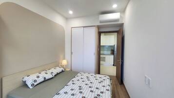 A bedroom with a bed, a bedside lamp, a wardrobe, and an air conditioning unit.