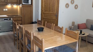 Eine Küche mit Holzausstattung, einer Mikrowelle, einem Herd und einem Esstisch mit Stühlen.
