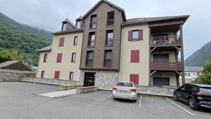 Un edificio de varios pisos con base de piedra, contraventanas rojas y balcones.