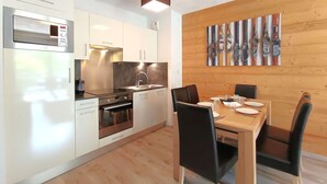 Una cocina moderna con armarios blancos, electrodomésticos de acero inoxidable y una mesa de comedor de madera con sillas negras.