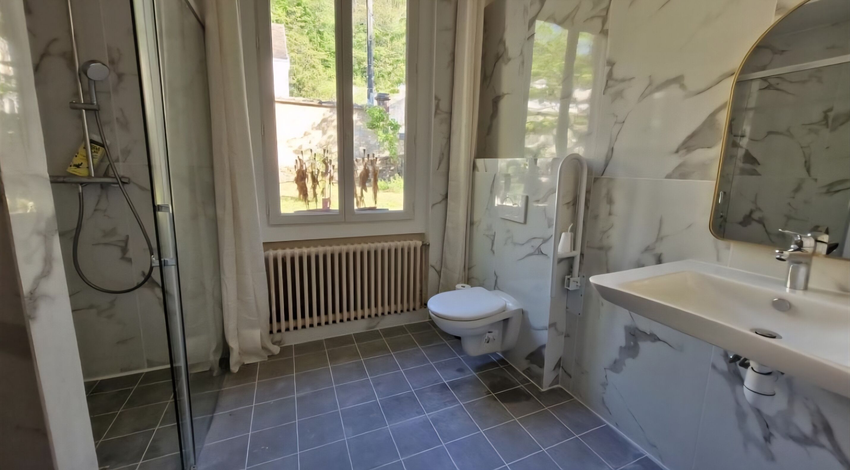 Un baño con ducha, inodoro, lavabo y ventana con vistas al exterior.