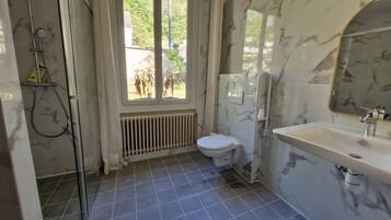 Un baño con ducha, inodoro, lavabo y ventana con vistas al exterior.