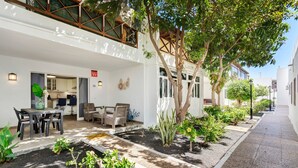 A modern building with a patio area, outdoor seating, and a variety of plants. - Apartment 'Romance' with Shared Pool, Private Terrace and Wi-Fi (Puerto del Carmen)