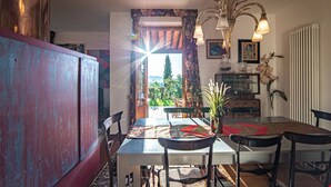 A dining area with a table set for four, surrounded by chairs, with a view of the outdoors through a doorway. - Villa Belvedere on the Tuscan Hills (Toscana)
