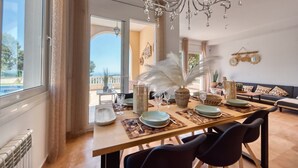 Un comedor con una mesa dispuesta para cuatro, una araña y vistas al exterior.
