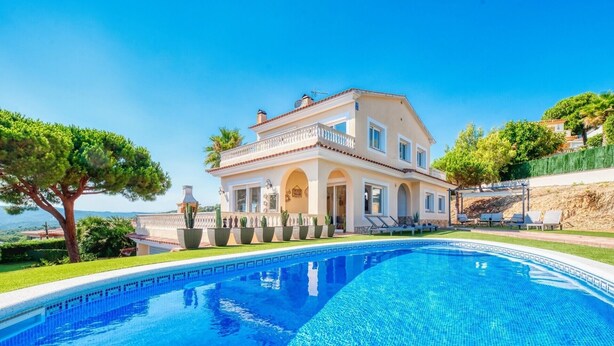 Una casa grande con piscina, balcón y vista al mar.