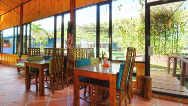 A wooden dining area with large windows and a view of greenery outside.