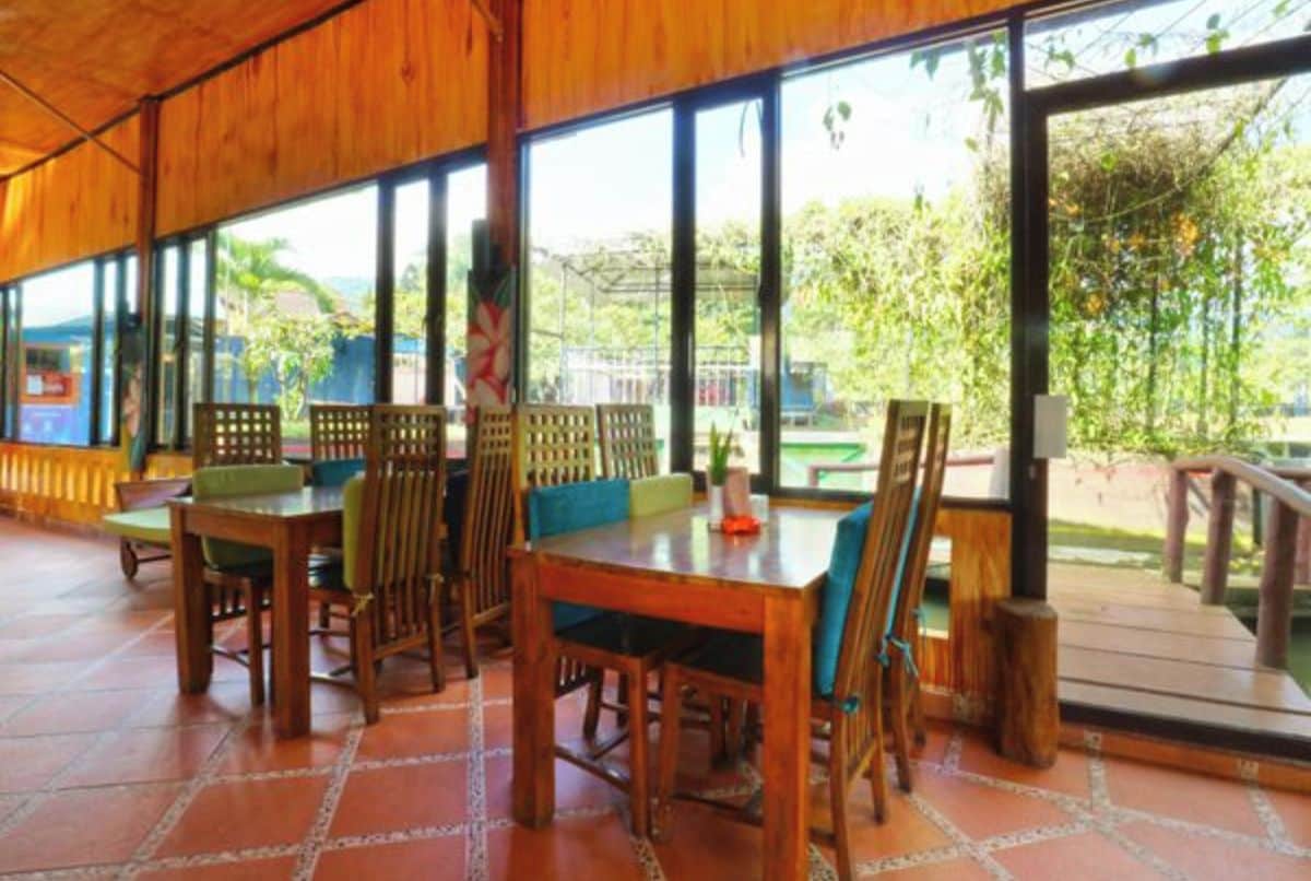 A wooden dining area with large windows and a view of greenery outside.