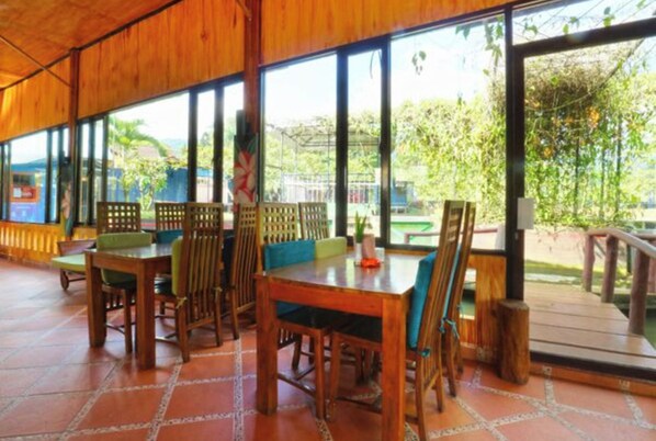 A wooden dining area with large windows and a view of greenery outside.