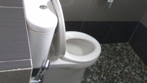 A toilet with a bidet attachment in a tiled bathroom.