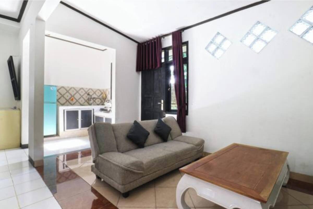 Un espacio habitable compacto con sofá, una pequeña mesa y una zona de cocina visible al fondo.