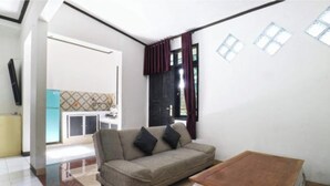 A compact living space with a sofa, a small table, and a kitchen area visible in the background.