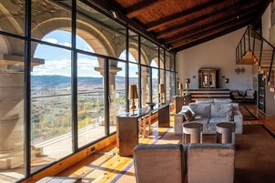 Una habitación amplia con ventanas grandes, techo de madera y una zona de estar moderna.