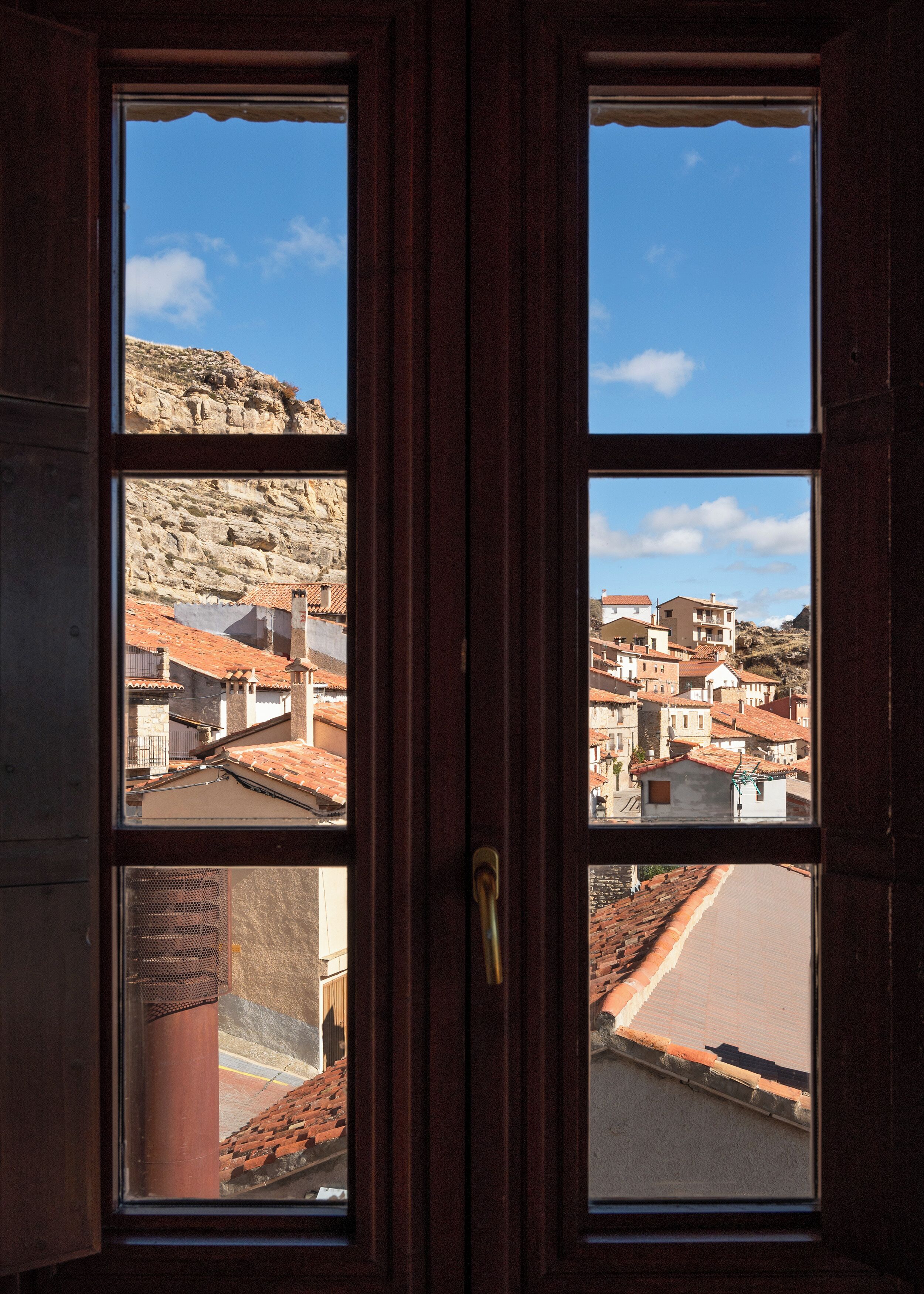 A wooden door with a view of a town through a window.